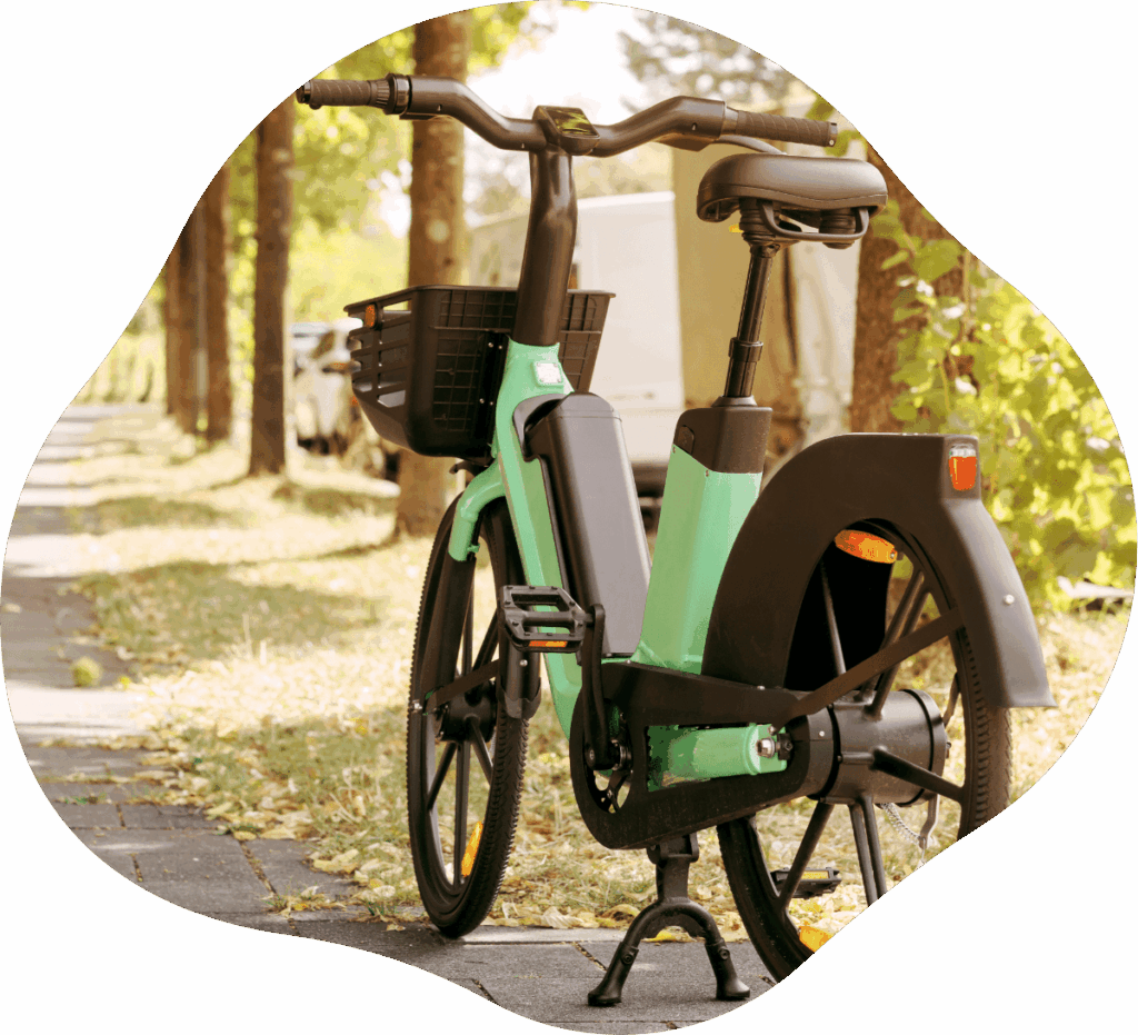Mintgrünes E-Bike ohne Gepäckträger mit Korb am Lenker steht in Baumallee