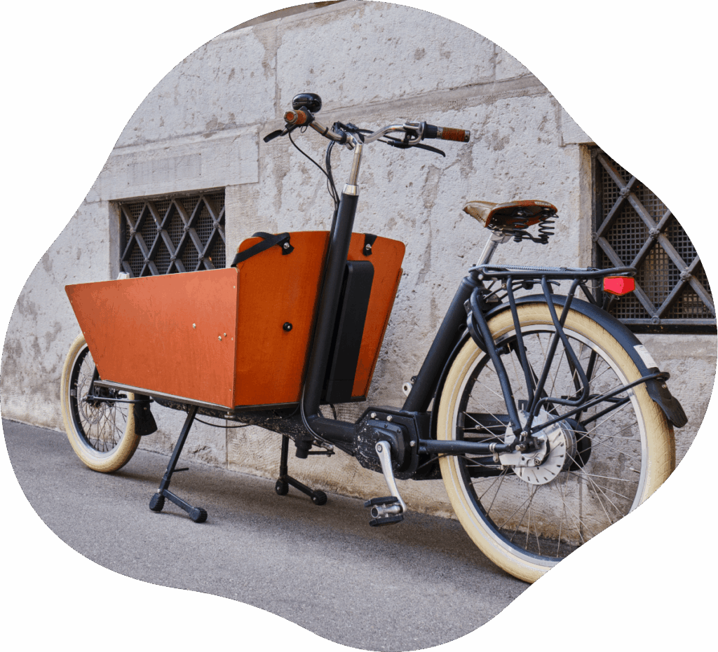 Schwarzes Cargobike mit Holzbox vor steiniger Hauswand