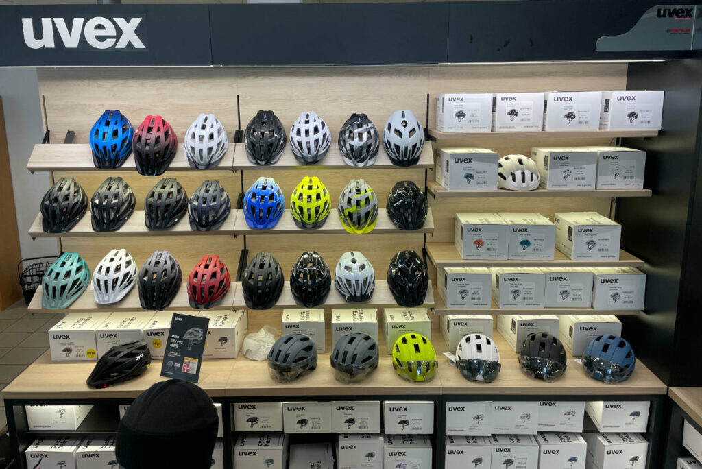 Beleuchtetes Regal mit zahlreichen Fahrradhelmen in unterschiedlichen Formen und Farben