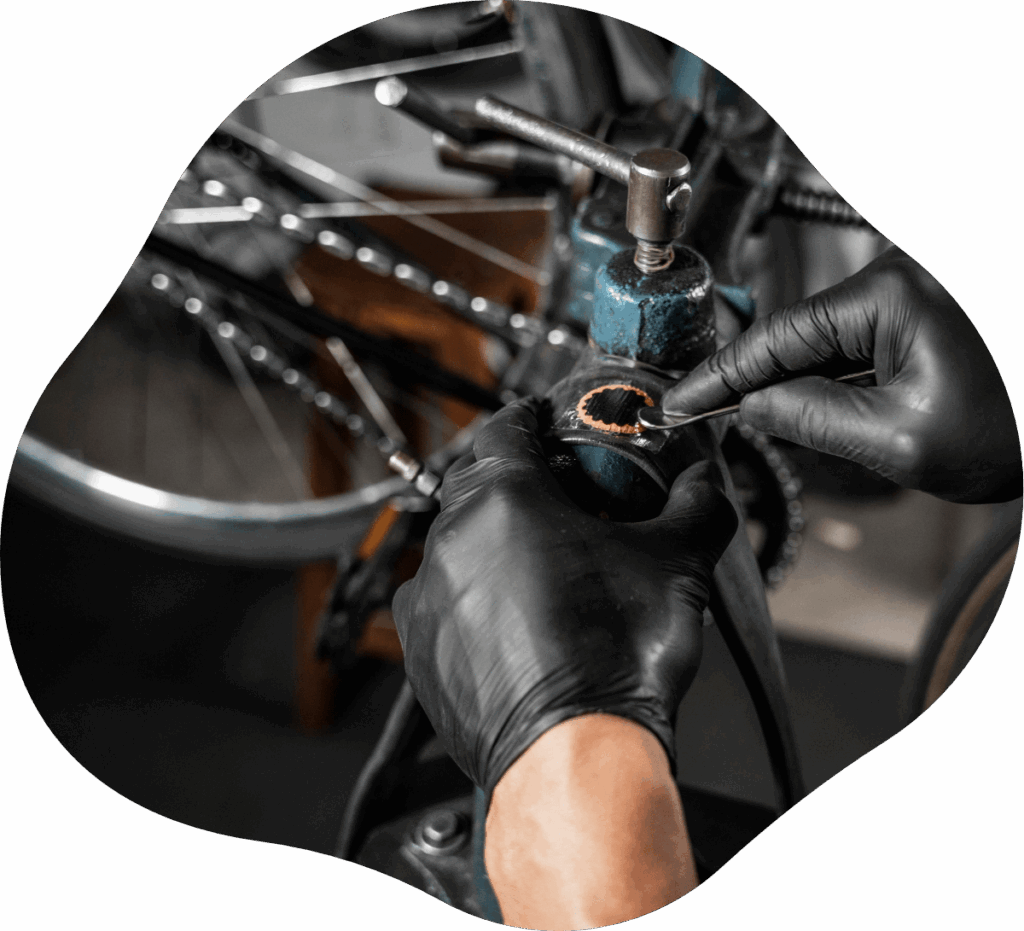 Fahrradmechaniker flickt Fahrradschlauch mit schwarzen Handschuhen und Flickwerkzeug